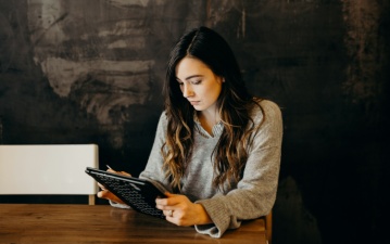 Eine Frau mit einem schwarzen Tablet an einem Tisch